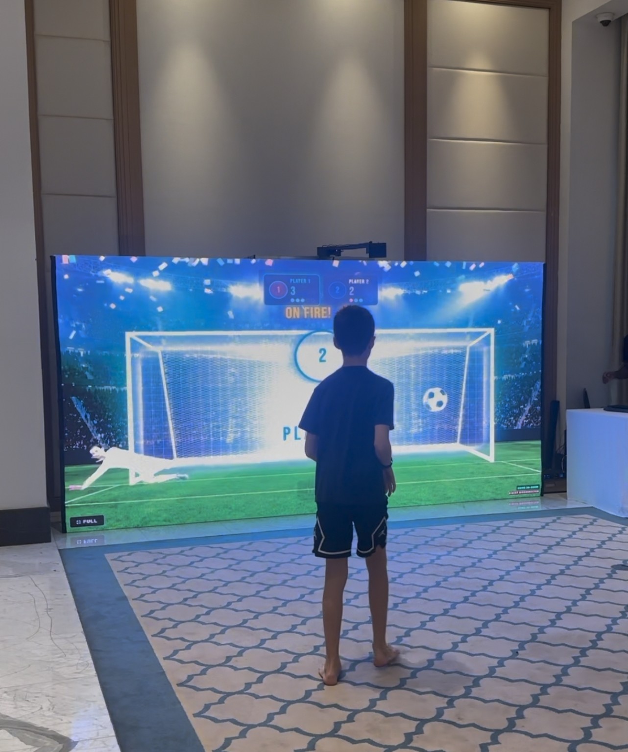 Guest participating in football motion game in front of LED screen